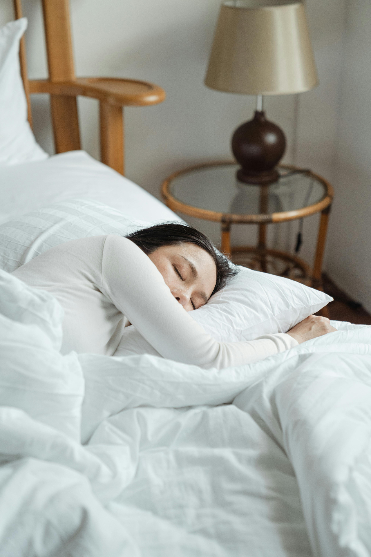 Woman sleeping peacefully in white bedding — bone broth before bed improves sleep quality with glycine and magnesium