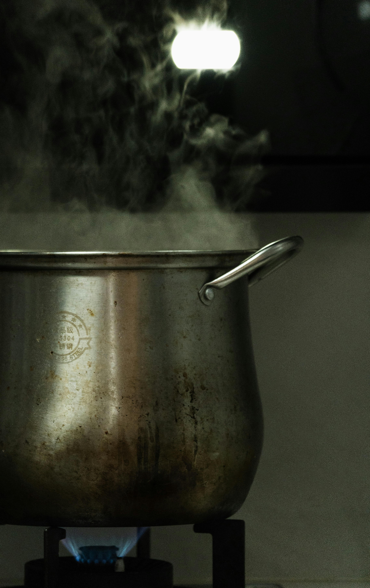 Marmite en inox mijotant sur une flamme à gaz avec de la vapeur qui monte — choisir un bon bouillon d'os